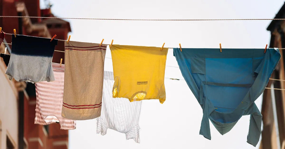 Shirts and towels drying on a clothesline against a blue sky