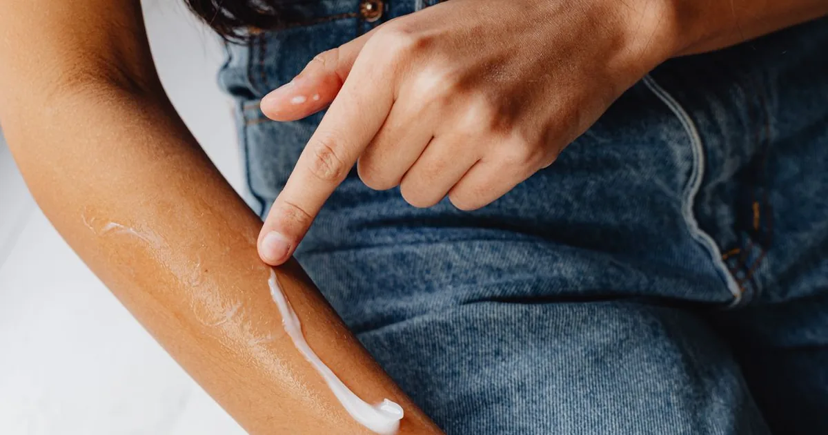 A person smoothing lotion along a bare forearm